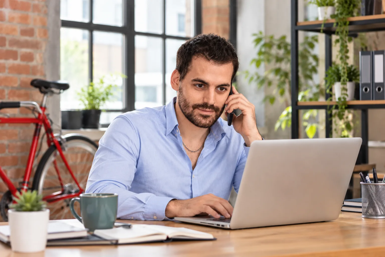 Un entrepreneur échange avec un client tout en travaillant sur son ordinateur
